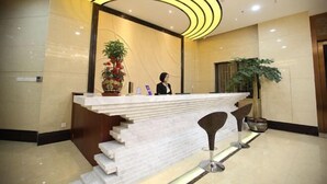 A reception area with a marble counter, a receptionist, and a modern light fixture.