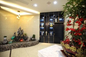 A reception area with a decorative fountain, a display of vases, and a potted plant. - Huamei Business Hotel (Tongxiang)