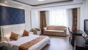 A hotel room with a bed, a sofa, a desk, and a TV.