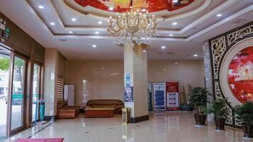 A hotel lobby with a chandelier, seating area, and potted plants.