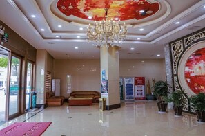 Un vestíbulo de hotel con candelabro, zona de estar y plantas en macetas.