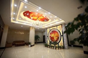A lobby with a chandelier, a large circular artwork, and a reception desk.