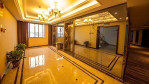 A hotel lobby with a polished floor, a chandelier, and a staircase.