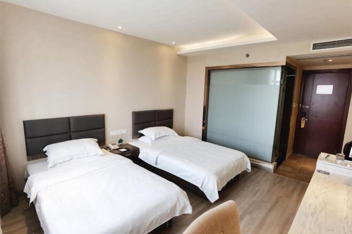 Ein Hotelzimmer mit zwei Betten, einem Schreibtisch und einer Schiebetür.