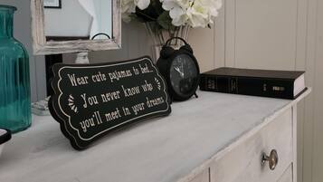 A vanity with a mirror, a clock, a sign, and a vase of flowers.