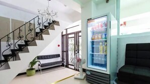 A modern living room with a staircase, a black sofa, a refrigerator, and a potted plant. - San Agustin Residences (Makati)