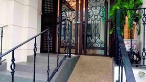 A staircase with ornate black railings leading to a door with decorative ironwork. - San Agustin Residences (Makati)