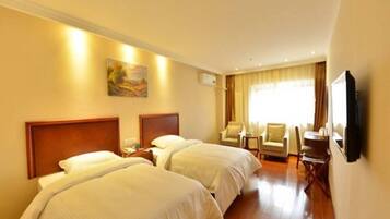 A hotel room with two beds, a flat-screen TV, a painting on the wall, and a window with curtains.