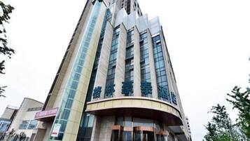A modern hotel with a curved entrance, multiple floors, and a prominent glass facade.