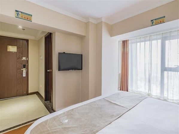 A hotel room with a bed, a television mounted on the wall, and a window with curtains. - Greentree Inn Beijing Changping District North China Electric Power University Business Hotel (Beijing)