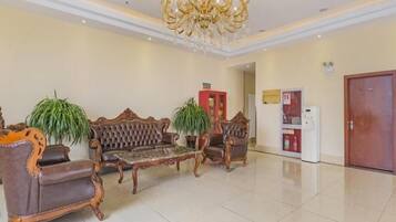 A spacious lobby with a chandelier, two sofas, a coffee table, and potted plants.