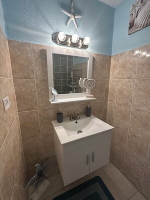 A bathroom with a white sink, a mirror, and a starfish decoration on the wall.