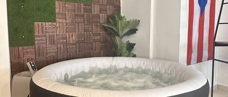 A hot tub with a control panel, a brick wall, a green wall, and a flag.