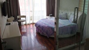 A bedroom with a bed, a desk, a chair, and a window with curtains. - Yandangshan Sunshine Hotel (Yueqing)