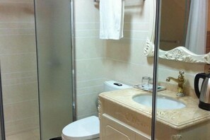 Une salle de bain avec une douche à parois de verre, des toilettes, un lavabo avec un miroir et une serviette accrochée au mur.