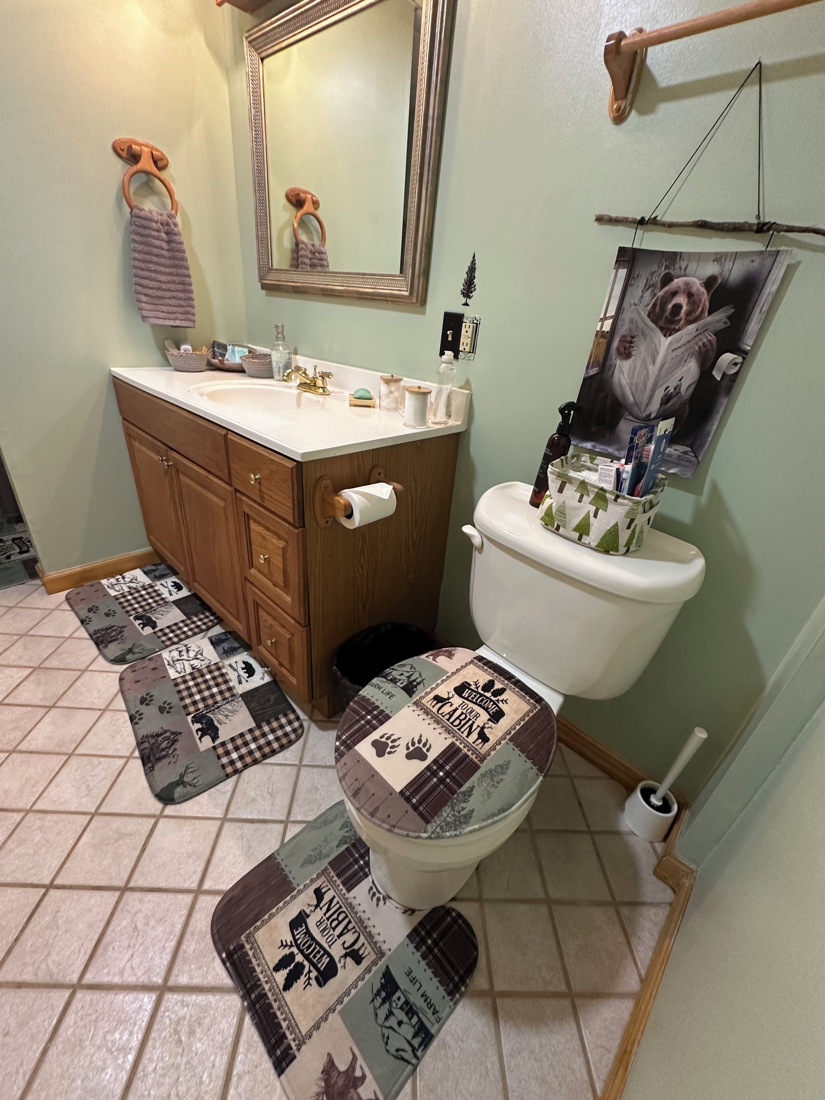 Une salle de bain avec un meuble-lavabo en bois, des toilettes dotées d’un couvercle décoratif, un miroir et un porte-serviettes.