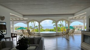 A spacious living area with a view of the ocean, a pool, and outdoor seating. - Palm Breeze Condo, Sugar Hill near Holetown - Beach Club Membership (Mount Standfast)