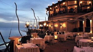 An outdoor dining area with tables set for guests, overlooking the sea. - Palm Breeze Condo, Sugar Hill near Holetown - Beach Club Membership (Mount Standfast)