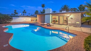 A modern pool area with a curved pool, lounge chairs, and a small building with a glass door. - Mid Century Modern near STRIP w Pool King Suite (Las Vegas)