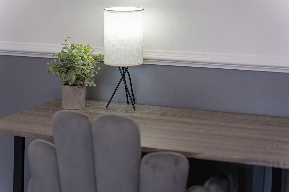 Una mesa con una lámpara y una planta en maceta.