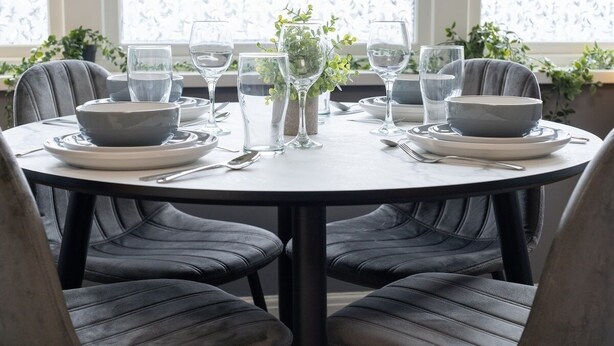 A round dining table with four chairs, set with bowls, plates, glasses, and cutlery. - Open Mind Property - Cosy Apartment with 3 Beds (Portsmouth)