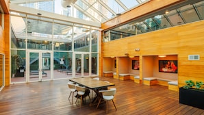 A spacious indoor area with a wooden floor, a large table with chairs, and a glass wall overlooking a cityscape. - Hudson Yards Hotel (New York)