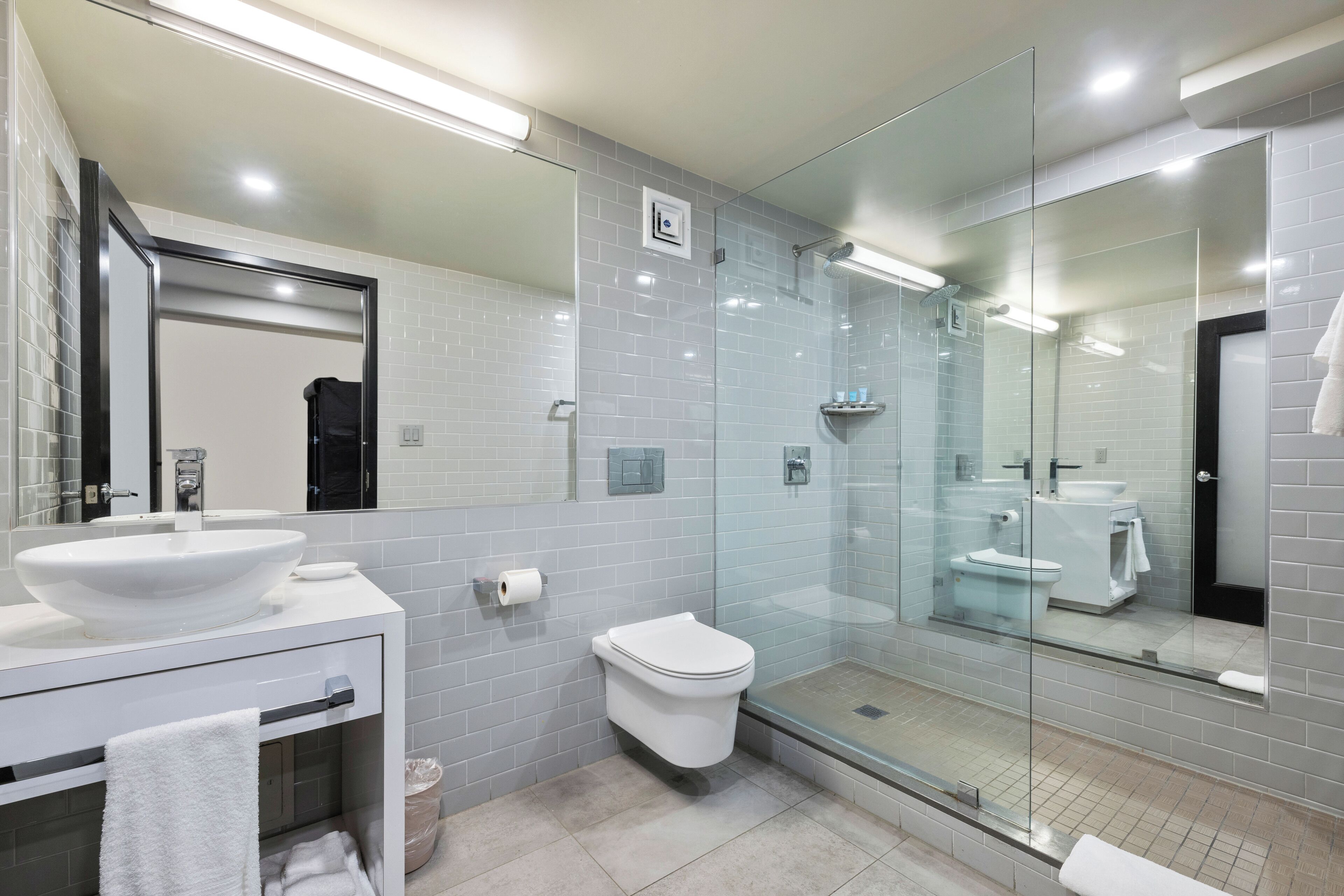 Une salle de bain moderne avec une douche à parois de verre, un lavabo blanc et des toilettes.