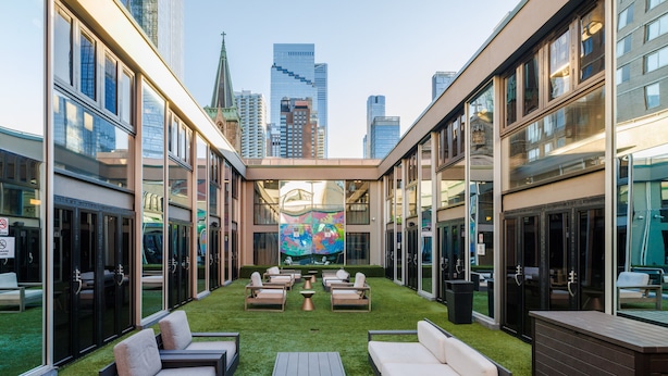 A courtyard with outdoor seating, a mural, and city views. - Hudson Yards Hotel (New York)