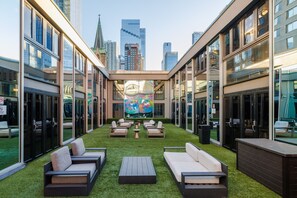 A courtyard with outdoor seating, a mural, and city views. - Hudson Yards Hotel (New York)