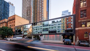 A modern building with a glass facade, adjacent to a brick building with a sign that reads "BABYS". - Hudson Yards Hotel (New York)