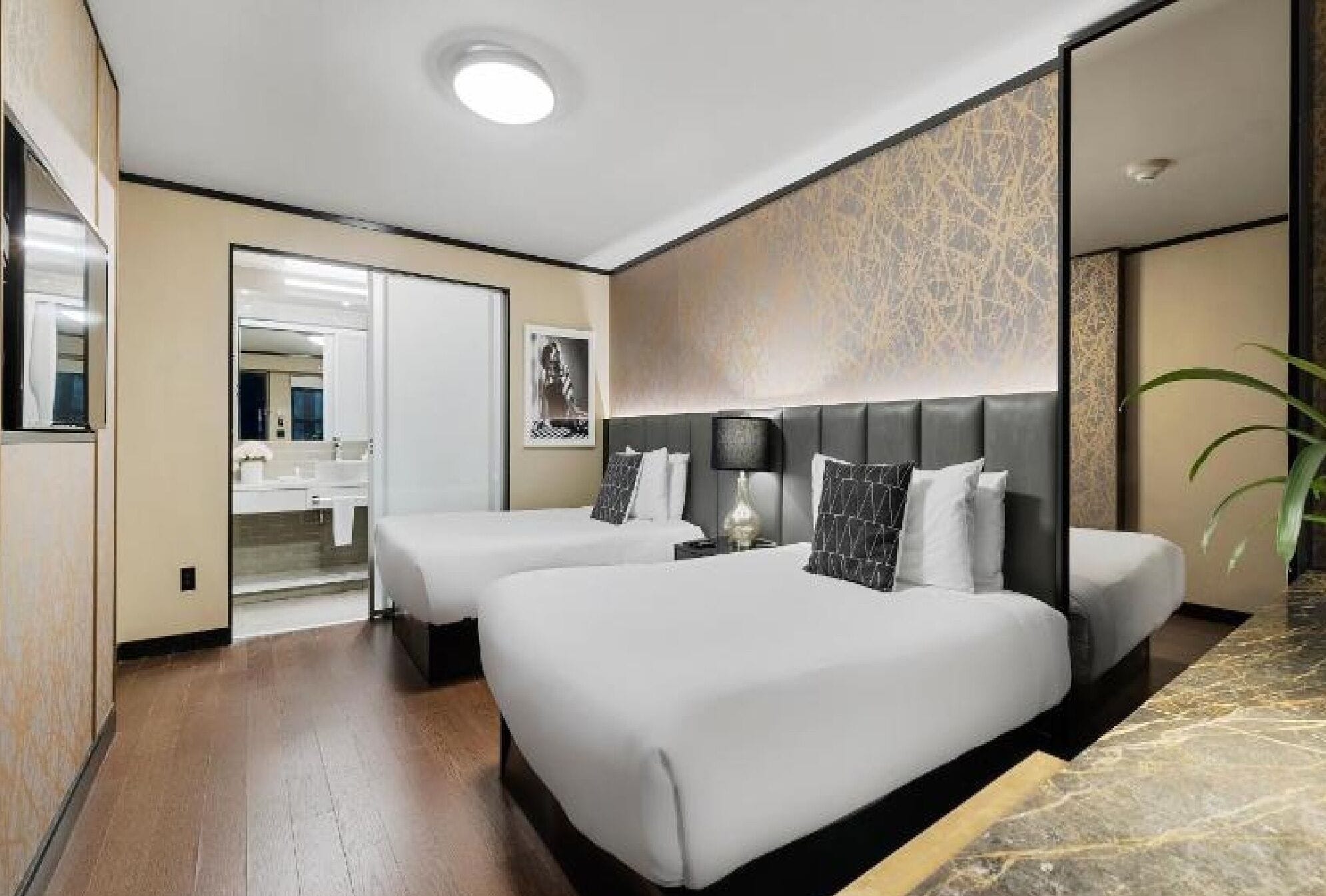 Une chambre d’hôtel avec deux lits, une salle de bain et un grand miroir.