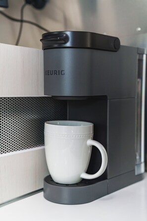 Una cafetera Keurig negra con una taza blanca sobre su base.