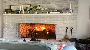 A living room with a white brick fireplace, a sofa, and a coffee table.