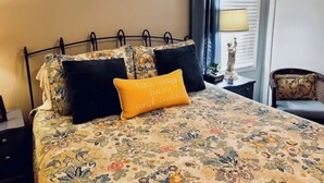A bed with floral bedding, a black metal headboard, and a decorative pillow with text.