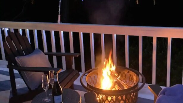 A deck with a fire pit, outdoor seating, and string lights.