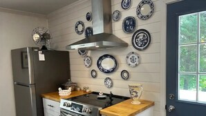 A kitchen with a stainless steel refrigerator, a stove, and an oven. There are decorative plates on the wall and a window with a view of trees.