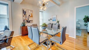 A modern dining area with a glass table, leather chairs, and a chandelier. - The Art Loft - A Luxurious 2-BdRm in the Heart of Historic Downtown Wilmington (Wilmington)