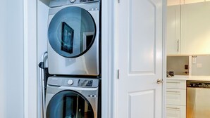 A laundry room with two stacked front-loading washing machines. - The Art Loft - A Luxurious 2-BdRm in the Heart of Historic Downtown Wilmington (Wilmington)
