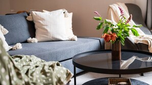 Un salon moderne avec un canapé gris, une table basse ronde noire et un vase rempli de fleurs.