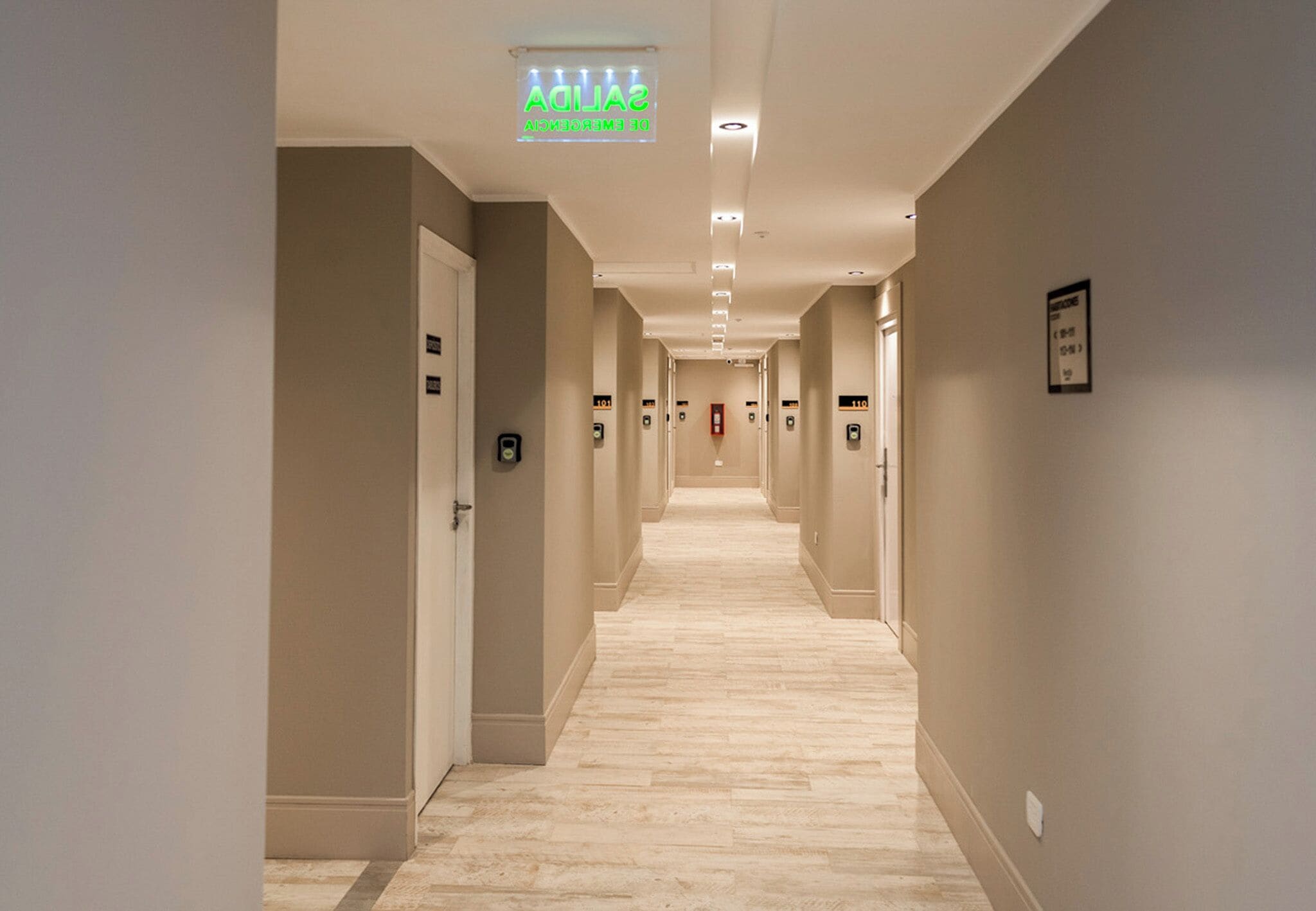 A hotel corridor with a sign indicating the emergency exit.