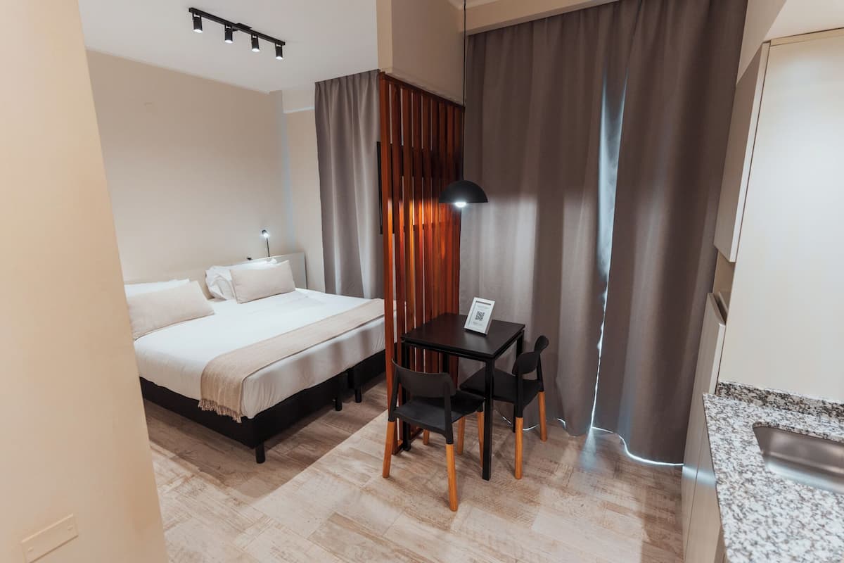 Een hotelkamer met een bed, een bureau met stoel, een lamp en een gordijn.