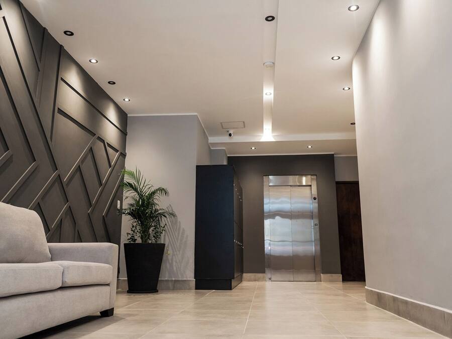 A modern lobby with a sofa, a potted plant, and an elevator.