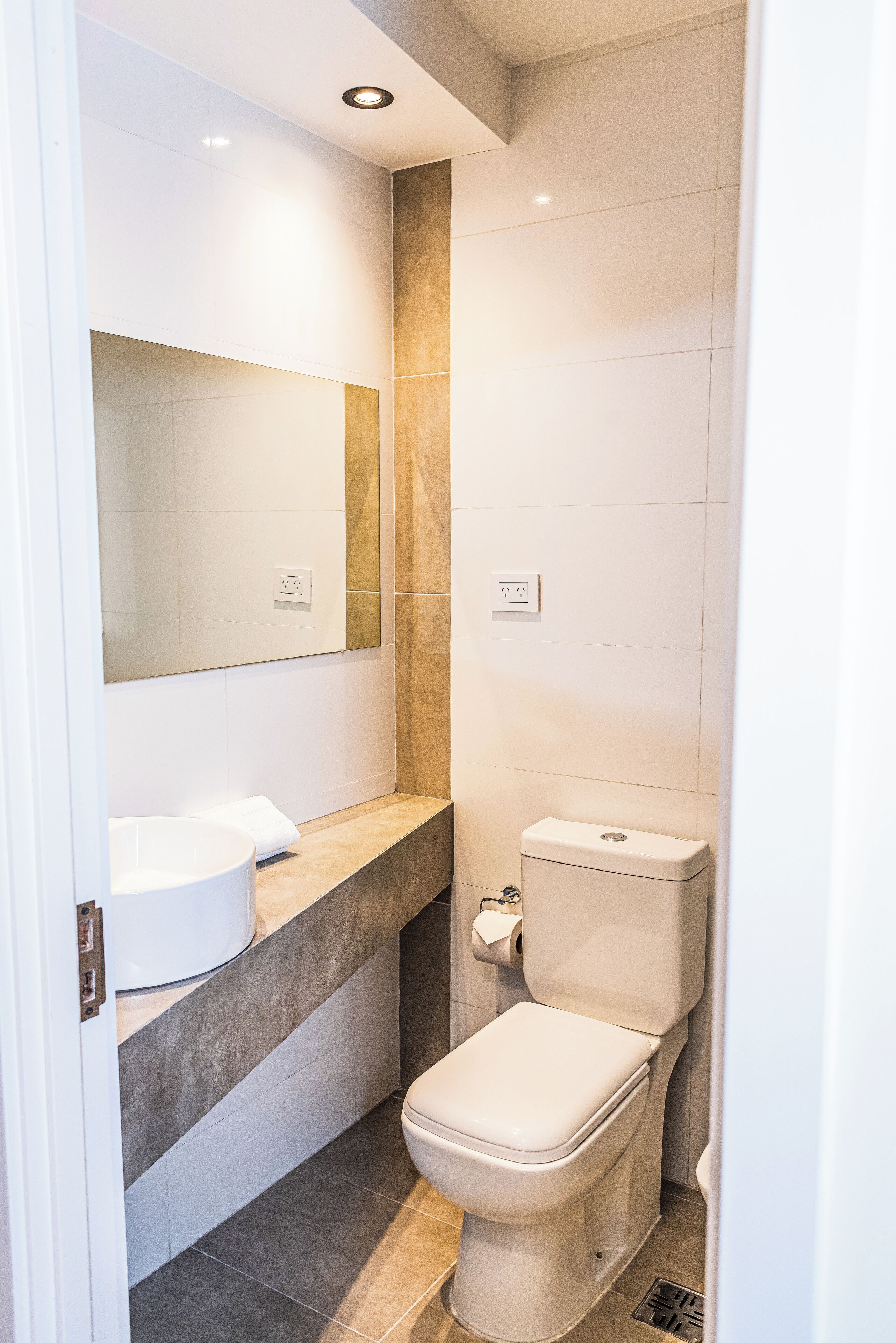 A compact bathroom with a toilet, sink, and mirror.
