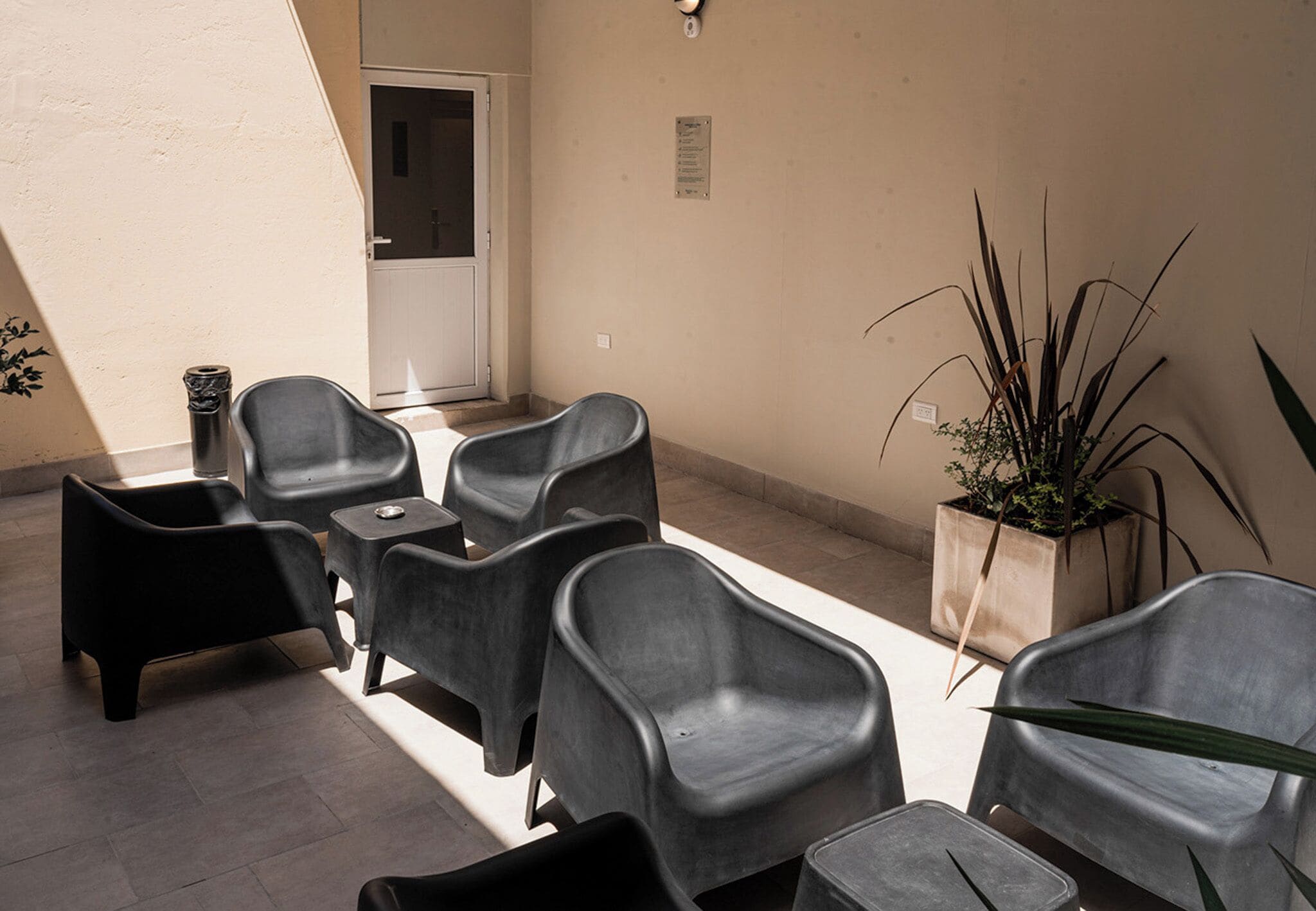 Een zithoek met meerdere stoelen en een kleine tafel, een potplant en een deur op de achtergrond.