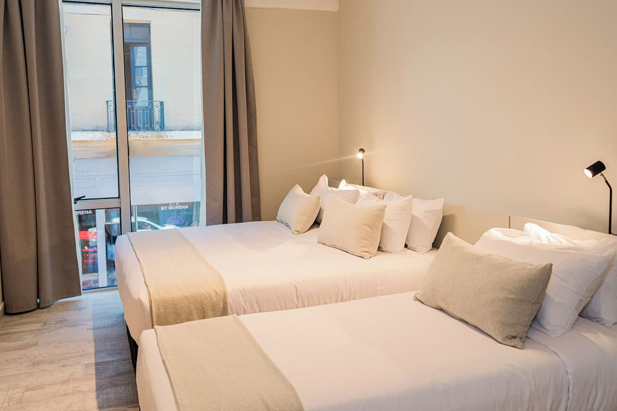 Een hotelkamer met twee bedden, een balkon en uitzicht op de stad.