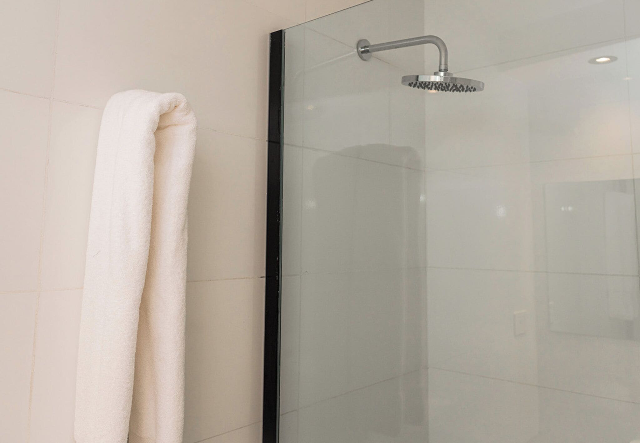 A glass-enclosed shower with a handheld showerhead.