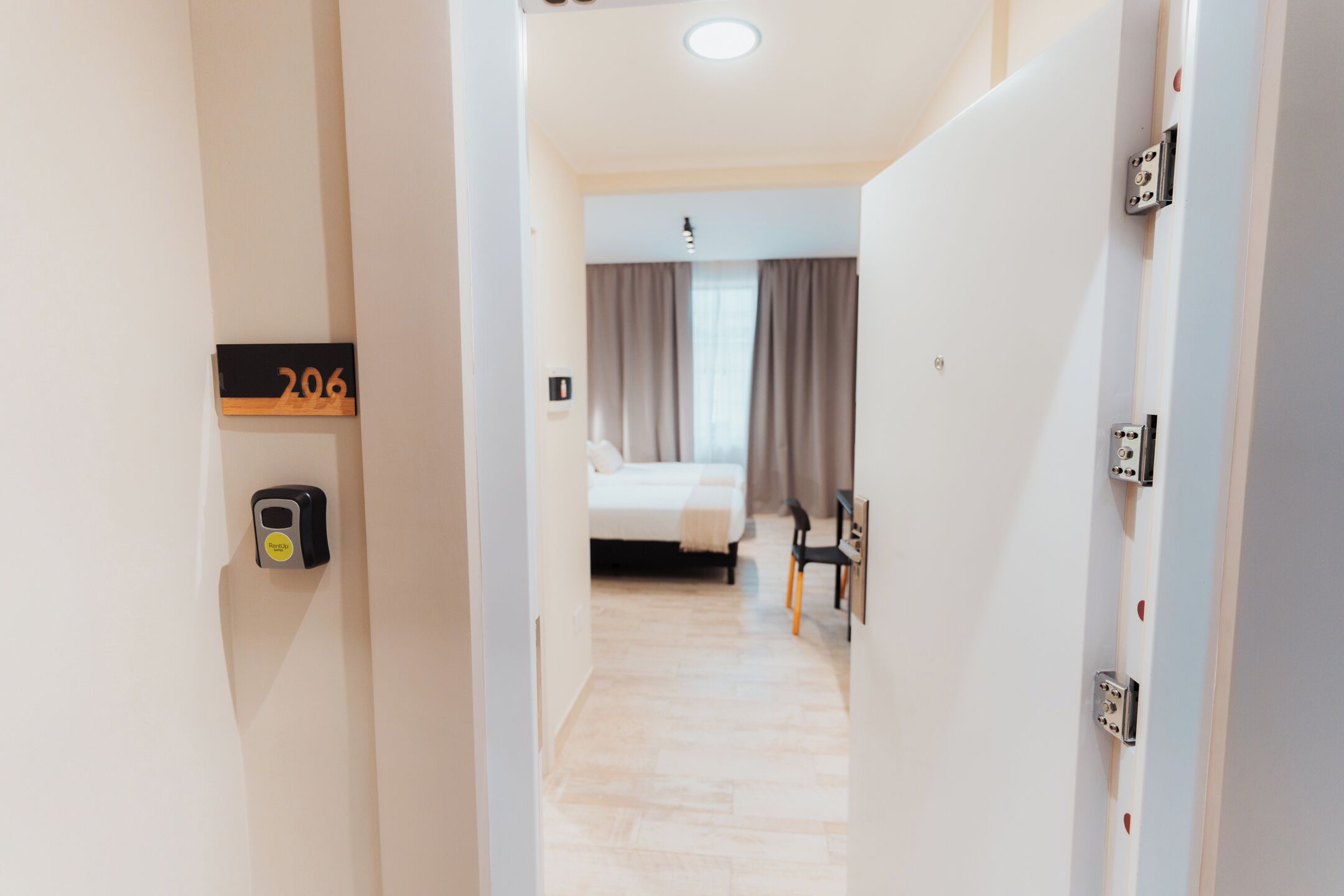 A hotel room with a bed, a desk, and a window with curtains.