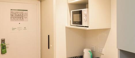 Una cocina con microondas, tetera y tostadora sobre la encimera.