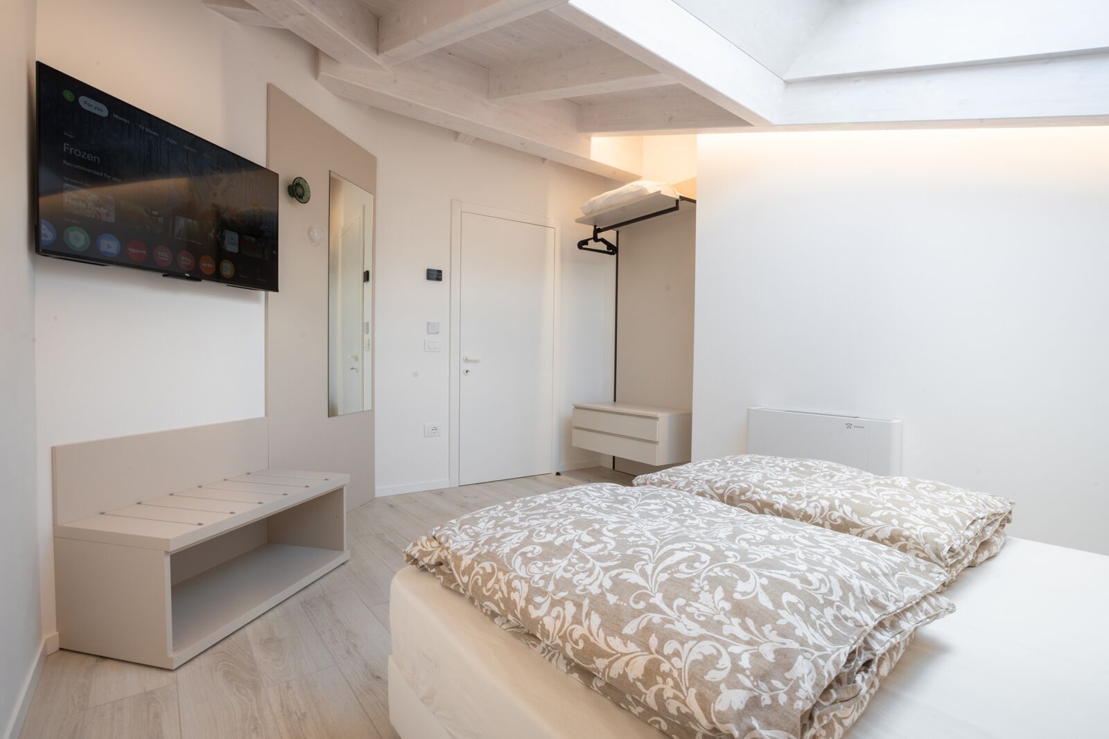 Un dormitorio con dos camas, televisión, armario y un banco.
