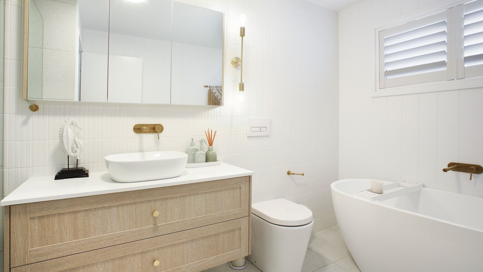 A modern bathroom with a white sink, vanity, and bathtub.